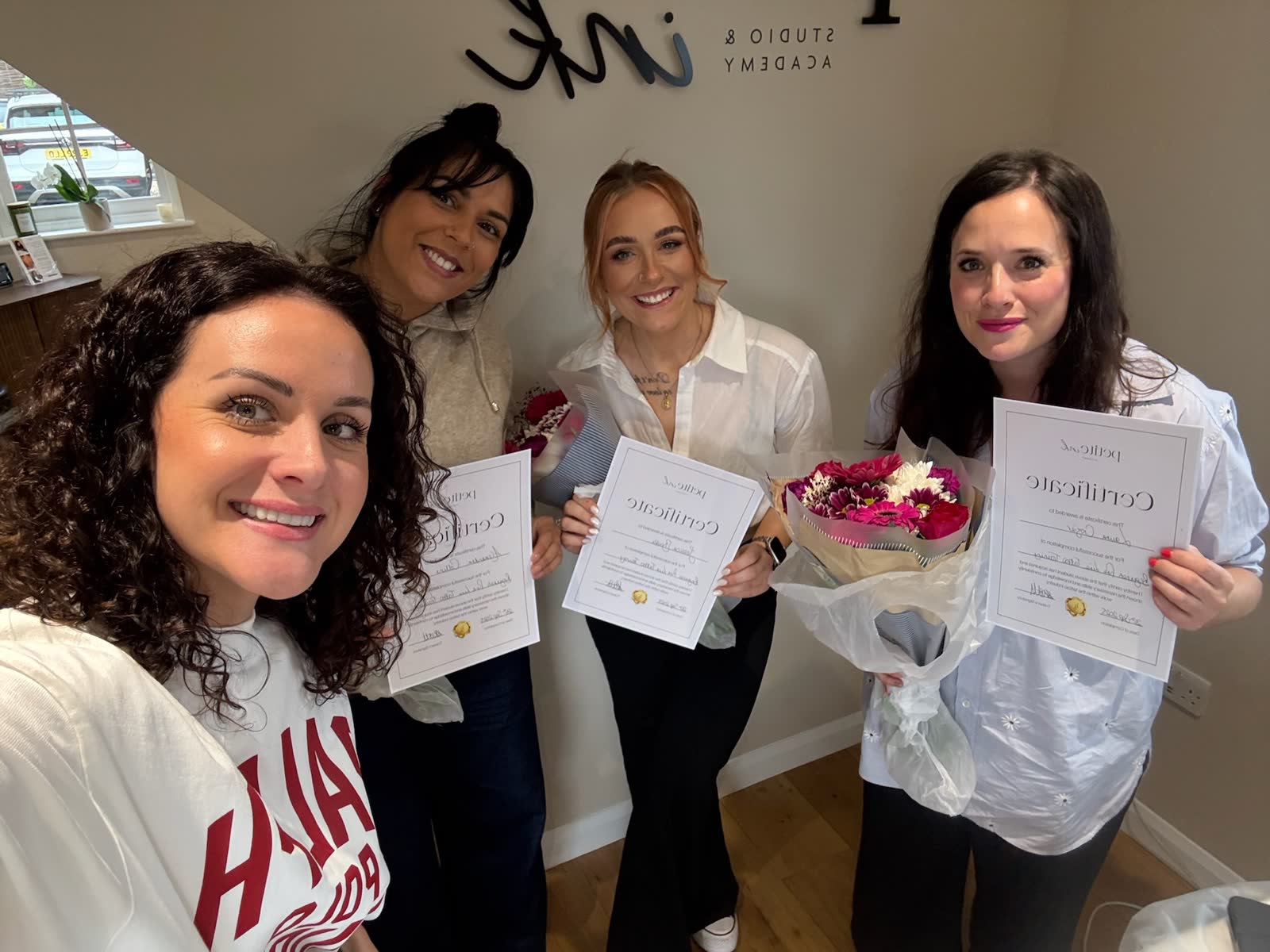 A cohort celebrating with flowers and certificates