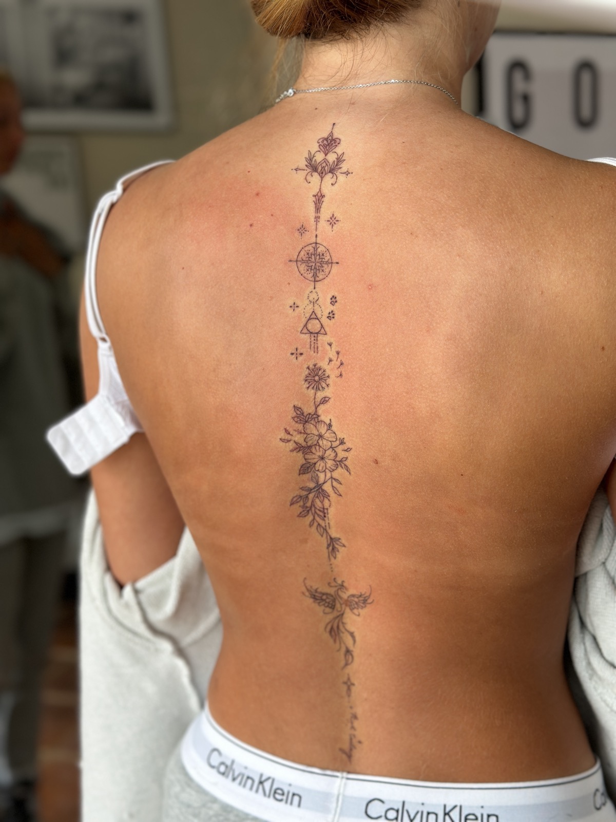 A fine line botanical spine tattoo