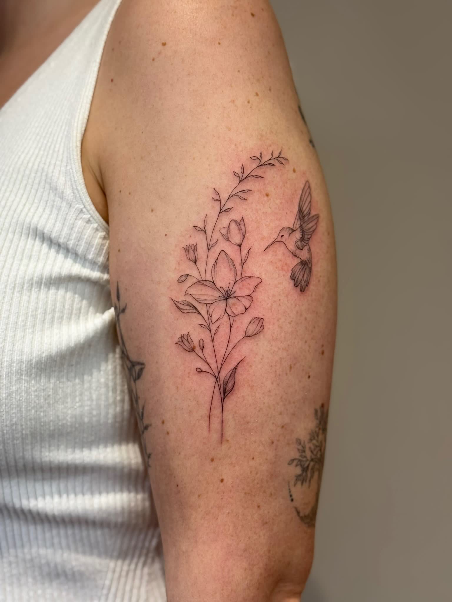 A fine line botanical bouquet on the upper arm